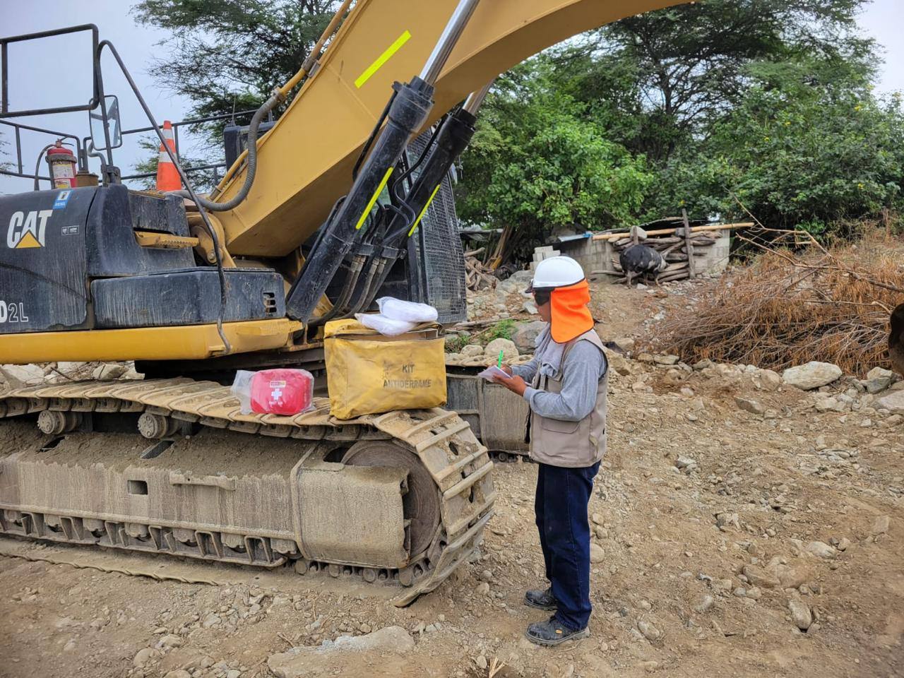 Ingeniero revisando kit antiderrame y checklist de seguridad junto a excavadora